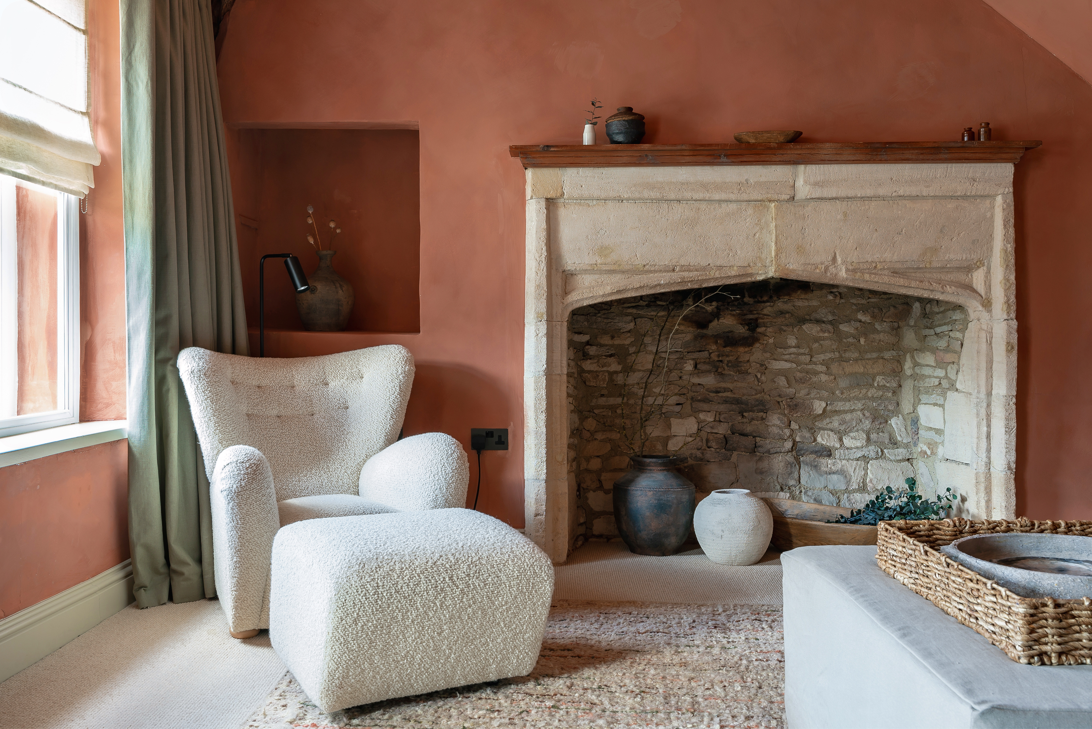 The Apartment suite with a white armchair and ottoman in front of a stone fireplace
