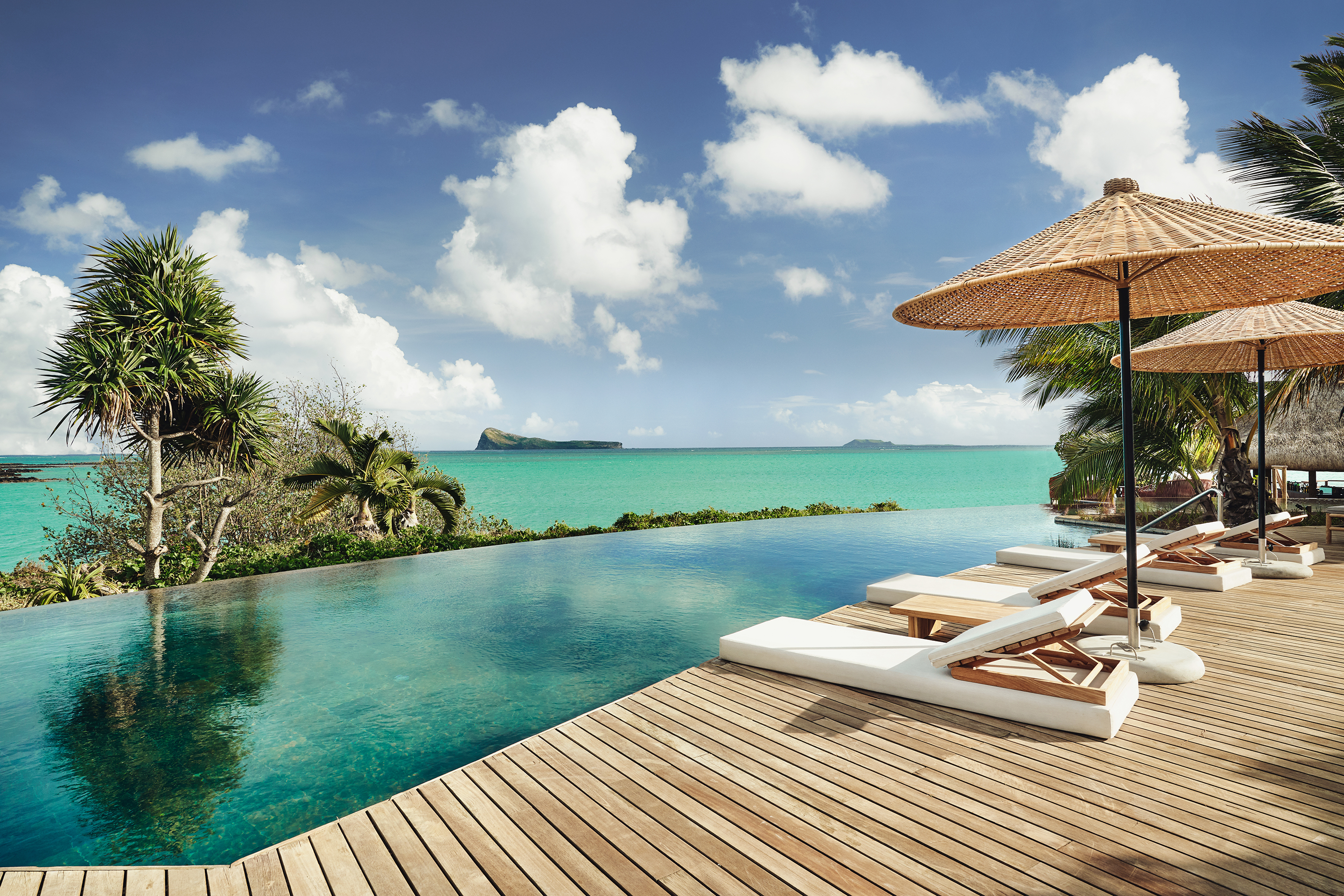 Infinity pool with lounge chairs and umbrellas overlooking the ocean.